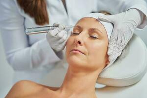 Woman having permanent eyebrows cosmetology treatment in salon photo