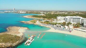 Ayia Napa, Zypern - - 15 .. April, 2023 - - Antenne fliegen Über Luxus Hotel Gebäude mit Pools durch Strand mit Insel Grün panorama.weiß Sand die meisten berühmt im Zypern - - Nissi Strand video