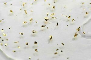 Gel background with gold particles, selective focus. Beauty skin care product close-up photo