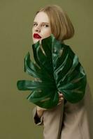 blonde woman green palm leaf coat bright makeup isolated background photo