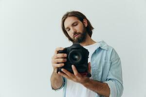 hombre hipster fotógrafo en un estudio en un blanco antecedentes mirando a el cámara pantalla y ajuste eso arriba para un foto disparar