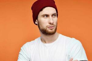 man in a white t-shirt and a hat tattoo on his arms orange background photo