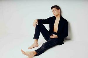 Man sitting on the floor wearing black jacket fashion stylish clothes studio lifestyle photo