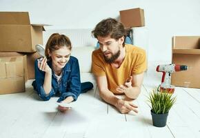 a man and a woman lie on the floor among boxes and a flower in a pot moving photo