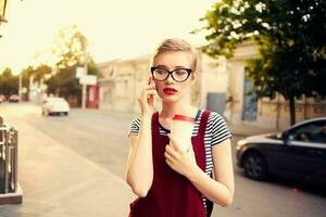 pretty woman with glasses on the street talking on the phone in summer photo