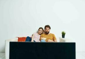 Man and woman on sofa with flower room interior and TV screen photo