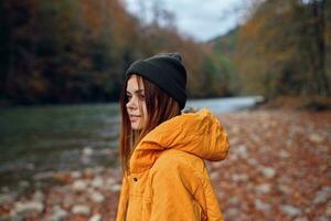 woman walks in the autumn forest in a yellow jacket mountains travel photo