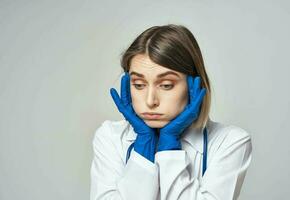 un enfermero en un médico vestido y azul guantes gestos con un estetoscopio alrededor su cuello foto