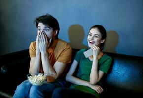 asustado hombre y contento mujer acecho televisión en el noche en el sofá foto
