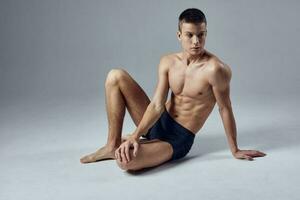 sporty man muscled body posing sitting on workout floor photo