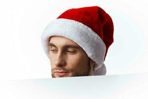 emotional man in a christmas hat with white mockup poster christmas light background photo