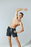 sport man with pumped up arm muscles bent to the side on gray background exercise workout photo