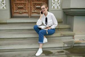 pretty woman with glasses walking around the city with a book education photo