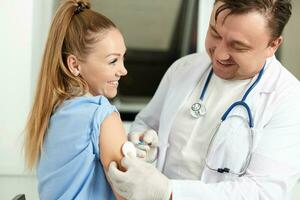 male doctor in a white coat injects a vaccine into the patient's hand covid vaccination photo