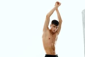 guy on a light background with arms raised up naked torso bodybuilder fitness photo