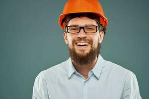 Bearded man in orange paint and glasses construction work blue background photo