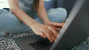 mulher é sentado em a chão e trabalhando em uma computador portátil. conceito do controlo remoto trabalhar. video