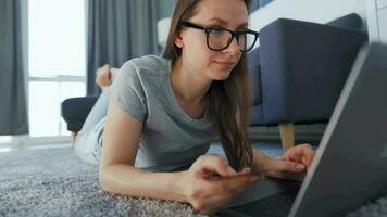 Woman is lying on the floor and working on a laptop. Concept of remote work. video