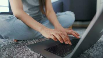 Woman is sitting on the floor and working on a laptop. Concept of remote work. video