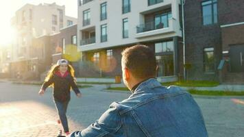 Daughter runs to dad and hugs him. Father picks up the child in his arms and circles her video