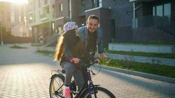 Dad is teaching daughter how to ride bicycle at sunset video