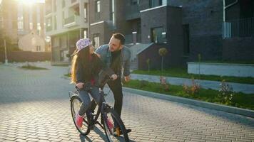 Dad is teaching daughter how to ride bicycle at sunset video