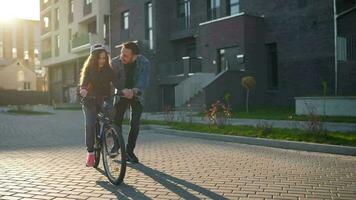 Dad is teaching daughter how to ride bicycle at sunset video