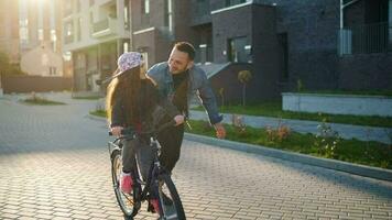 Dad is teaching daughter how to ride bicycle at sunset video