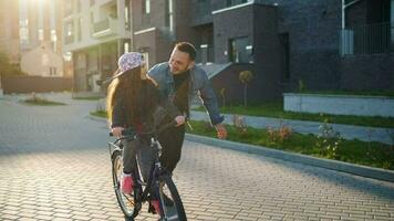 Dad is teaching daughter how to ride bicycle at sunset video