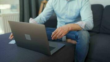 Man sitting on a cozy sofa and working on laptop and smartphone. Concept of remote work. Home Office video