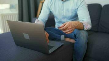 uomo seduta su un' accogliente divano e Lavorando su il computer portatile e smartphone. concetto di a distanza opera. casa ufficio video