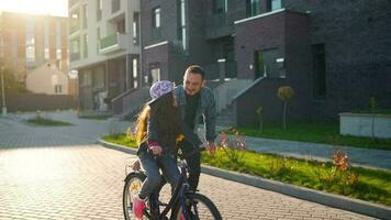 Dad is teaching daughter how to ride bicycle at sunset video