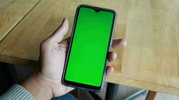 mano de hombre joven usando un teléfono inteligente con pantalla verde en el café video