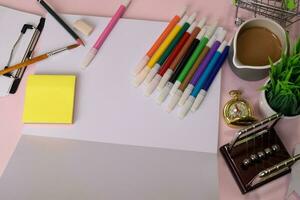 Top view of the open notebook with a marker drawing on a pink table, preparing to do homework. Drawing Working Desk Concept photo