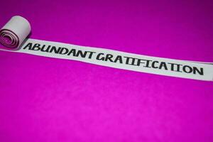 Abundant Gratification text, Inspiration and positive vibes concept on purple torn paper photo