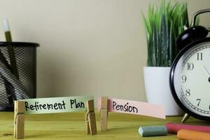 Retirement Plan and Pension. Handwriting on sticky notes in clothes pegs on wooden office desk photo