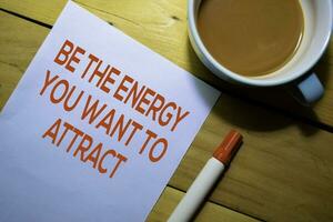 Be The Energy You Want To Attract text on the paper isolated on Table background photo