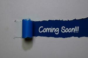 Coming Soon write on blue and white torn paper photo