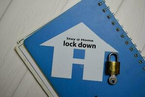 Stay at home and Lock Down write on a home made from paper isolated on Office Desk. photo