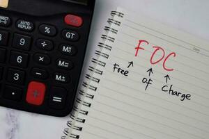 FOC - Free Of Charge write on a book isolated wooden table. photo