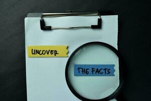 Uncover - The Facts write on sticky notes isolated on office desk. photo