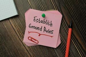 Establish Ground Rules write on sticky note isolated on Wooden Table. photo