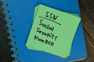 SSN - Social Security Number write on sticky notes isolated on Wooden Table. photo