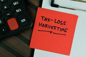 Tax-Loss Harvesting write on sticky notes write on a sticky notes isolated on Wooden Table. photo
