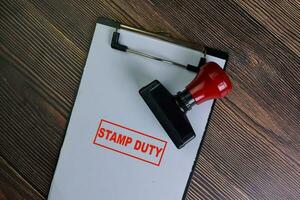 Red Handle Rubber Stamper and Stamp Duty text isolated on wooden table. photo