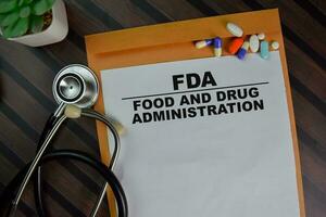 FDA - Food and Drug Administration text on document above brown envelope and stethoscope. Healthcare or medical concept photo