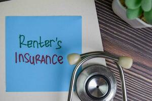 Renter's Insurance write on sticky notes isolated on Wooden Table. photo