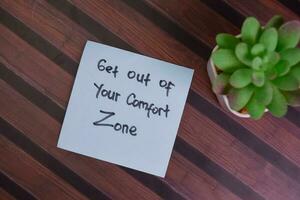 Get Out of Your Comfort Zone write on sticky notes isolated on Wooden Table. photo
