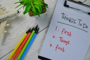 Things To Do - First Things First write on a paperwork and supported by additional services isolated on Wooden Table. photo