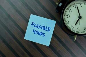 Flexible Hours write on sticky notes isolated on Wooden Table. photo